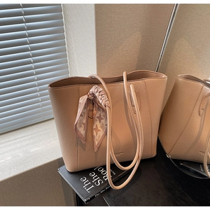 Close-up of beige lychee leather tote bag with elegant houndstooth silk scarf detail