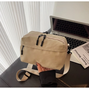 Detail of light beige nylon crossbody bag with multi-zipper compartments and adjustable strap