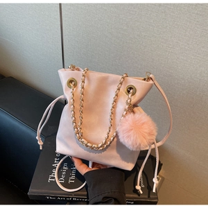 Détail du sac seau en cuir rose avec chaîne dorée et breloque pompon en peluche rose