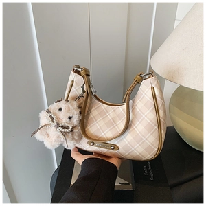 Detailed view of checkered crescent bag with brown leather strap and bunny charm