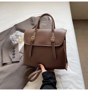 Detail showing high-quality dark brown leather texture and gold buckle on retro backpack