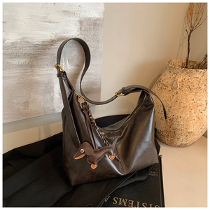 Detail view of large dark brown hobo bag featuring soft leather texture and dog-shaped charm