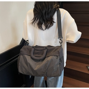 Rear view of a large grey travel bag with grid pattern on a crossbody strap