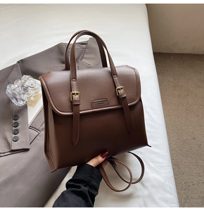 Detail of dark brown vintage leather backpack with dual buckle straps and textured finish