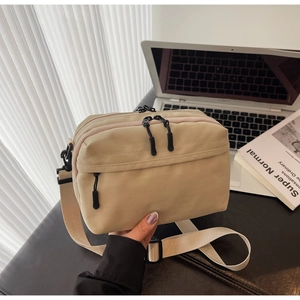 Detail of beige nylon crossbody bag with multi-zipper compartments and wide strap