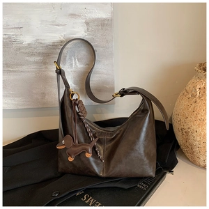 Detail of vintage brown leather underarm bag with a cute dachshund puppy pendant decoration