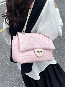 Pink quilted shoulder bag with gold chain strap shown in a stylish street style view