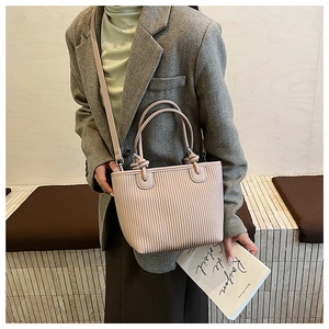 Detail view of pink pleated leather bucket bag with silver buckles and crossbody strap