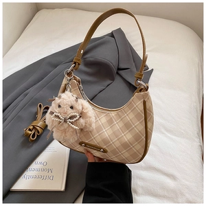 Detail of checkered canvas tote bag featuring a pink plush rabbit charm and shoulder strap