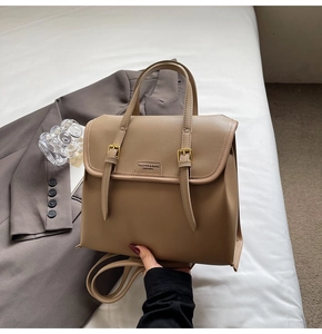 Close-up of khaki faux leather texture and gold buckle detail on a retro backpack