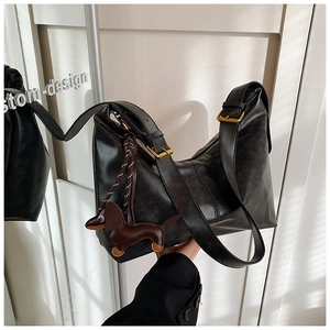 Detail of a vintage black hobo bag with adjustable strap and cute leather dog pendant