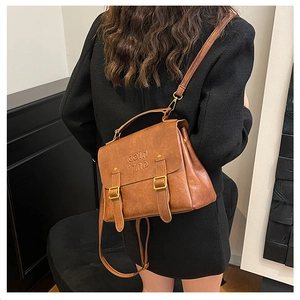 Detail of vintage brown leather backpack with COIN relief and top handle on black coat