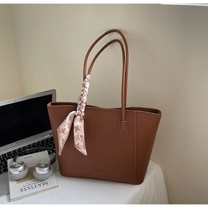 Close-up of brown litchi pattern leather tote bag with stylish silk scarf and fashion text