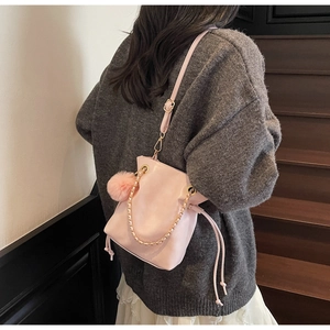 Détail du sac seau rose à cordon avec chaîne dorée et pendentif boule en peluche