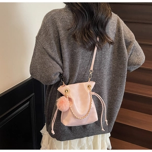 Vue détaillée du sac seau rose à cordon avec pompon décoratif et chaîne dorée