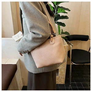 Detail showing vertical pleat texture and knot design on light pink faux leather tote