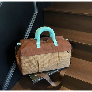 Close-up of large travel bag with brown and beige plaid pattern on wooden stairs