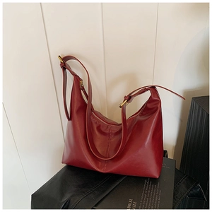 Detail of dark red leather underarm bag with gold metal buckle on a magazine background