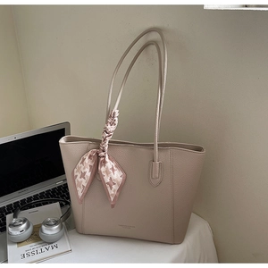 Detail shot of beige leather tote bag with lychee texture and pink checkered silk scarf