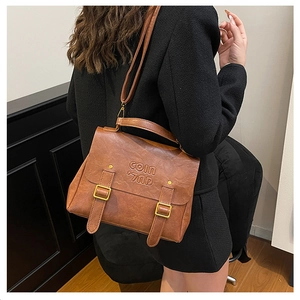 Detailed close-up of brown PU leather bag featuring COIN embossing and retro gold buckles