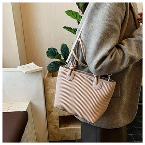 Detail of light pink bucket bag with vertical pleats and decorative knot on strap