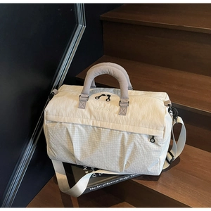 Detailed macro view of the cream and gray travel bag with NINGJIA embroidery and strap