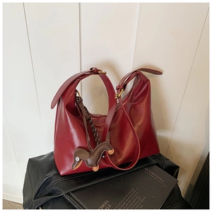 Detail of burgundy hobo shoulder bag with smooth leather finish and cute dog charm