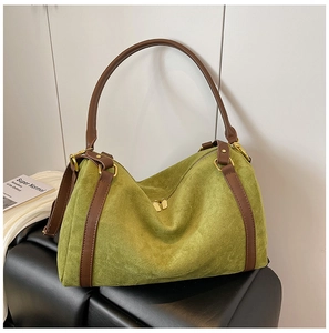 Dettaglio della borsa tote in pelle scamosciata verde con manici marroni e metallo oro