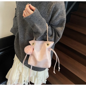 Détail du sac seau en similicuir rose avec chaîne dorée et breloque pompon en peluche