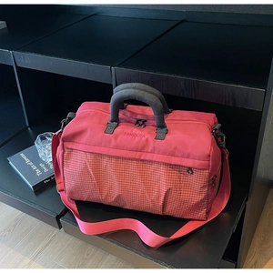 Detail of red quilted travel bag with reinforced handles and detachable shoulder strap