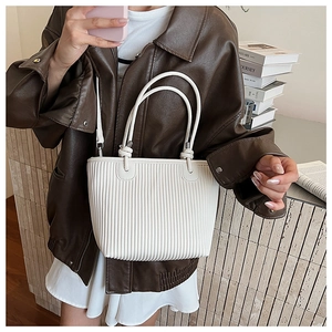 Detailed view of white pleated tote bag texture and dual handles worn by a model