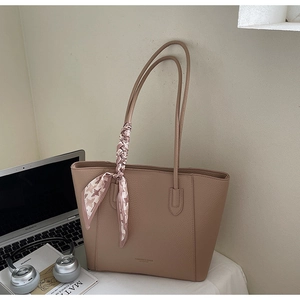 Detail of khaki leather tote with houndstooth silk scarf on a desk with laptop