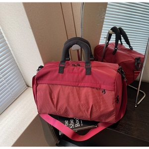 Detail of burgundy travel bag with white checkered pattern and durable handles