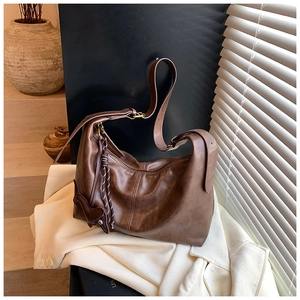 Close-up of retro brown leather hobo bag with adjustable strap and cute rabbit charm
