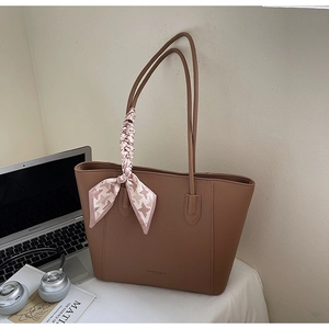 Detail of dark brown lychee leather tote with decorative silk scarf and fashion lettering