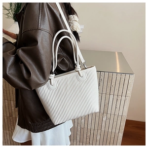 Detail of white pleated tote bag with vertical textures and thin adjustable shoulder strap