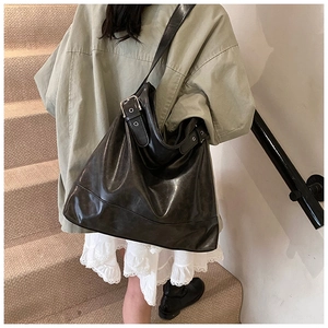 Detail of dark brown tote bag with adjustable shoulder strap and silver metal buckle
