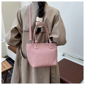 Detail of pink pleated bucket bag showing vertical wave texture and slim shoulder strap