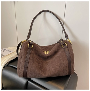 Dettaglio della borsa tote in pelle scamosciata marrone con hardware dorato e manici in pelle