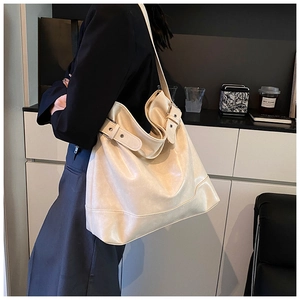 Detailed view of cream-colored leather tote bag with adjustable side strap buckle