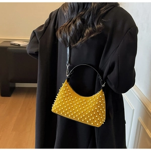 Detail of yellow hobo bag with pearl embellishments and black leather strap