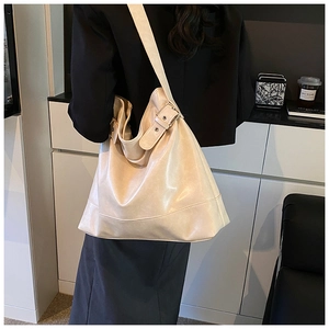 Detail view of the adjustable wide shoulder strap with metal buckle on a cream tote bag