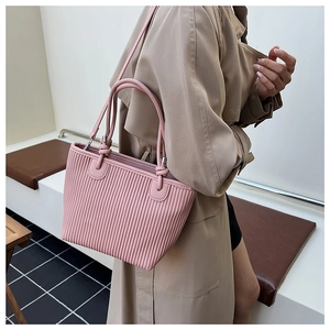 Detailed side view of pink pleated woven tote bag with slim handles worn by a model