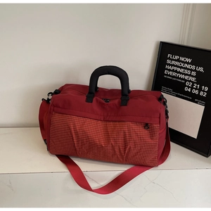 Detail view of burgundy travel bag showing nylon texture and red checkered fabric stitching