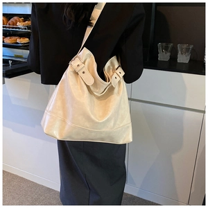 Close-up of a large beige leather tote bag with silver buckle on a stylish model