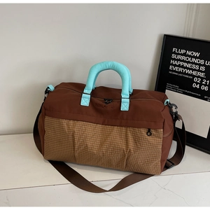Close-up of contrast large travel bag with light blue padded handles and brown checkered base