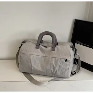 Close-up of large travel bag featuring beige and grey checkered pattern and shoulder strap