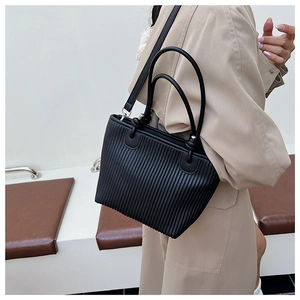 Close-up of black leather tote bag featuring unique vertical pleated texture and silver hardware