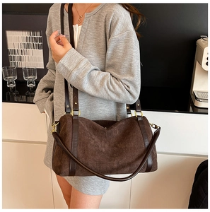 Dettaglio di una borsa tote in pelle scamosciata marrone scuro con hardware dorato su modella