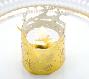 Detailed view of a golden metal tea light holder with laser-cut elk and snowflake patterns